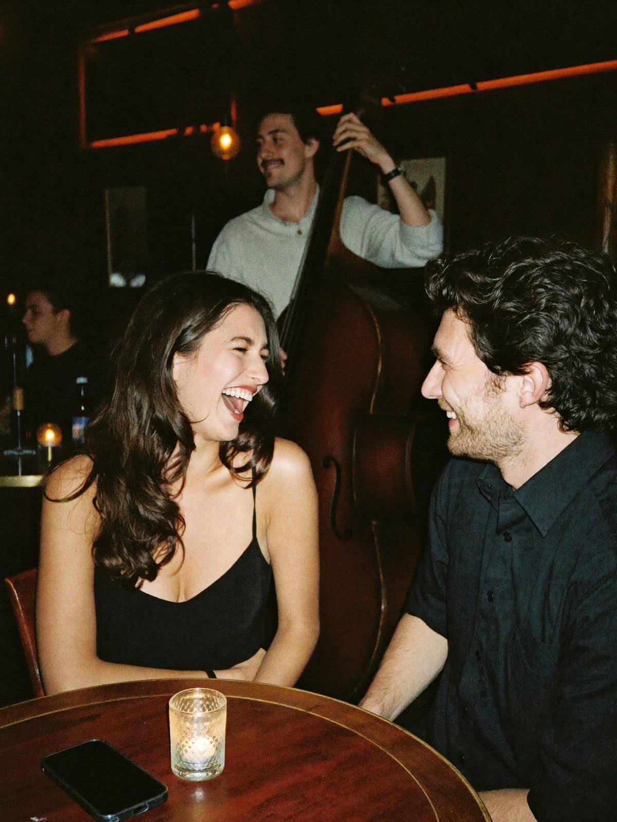 Paulina y Rafael riéndose en un bar de jazz, con el contrabajo detrás